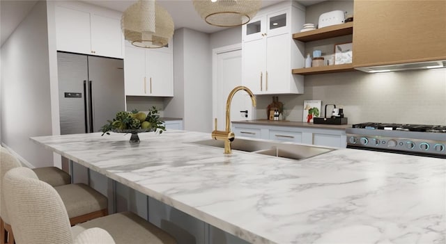 kitchen with white cabinets, a sink, a kitchen bar, open shelves, and range