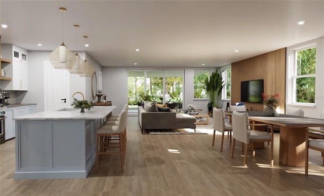 kitchen with a sink, a wealth of natural light, open floor plan, white cabinetry, and light countertops