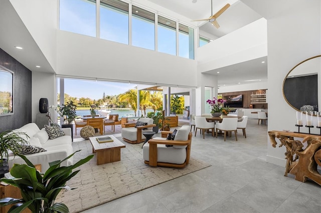 living room featuring ceiling fan, a towering ceiling, and a wealth of natural light