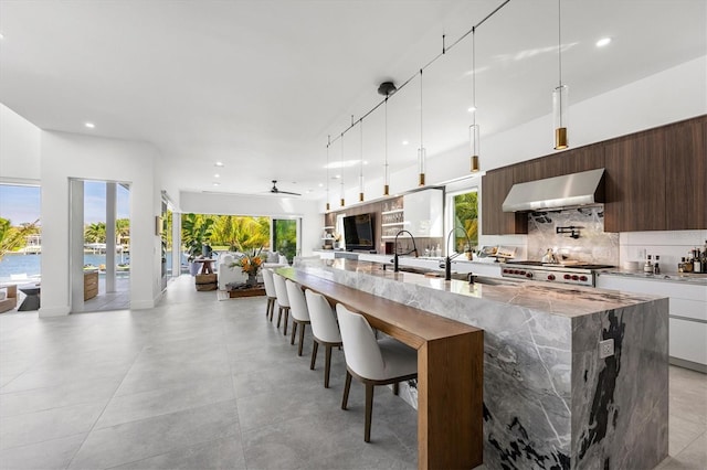 kitchen with wall chimney exhaust hood, a kitchen bar, plenty of natural light, and backsplash