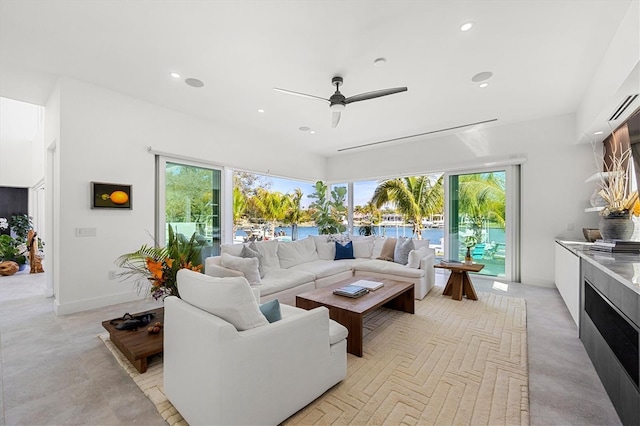 living room featuring ceiling fan, a water view, and a healthy amount of sunlight