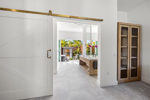 corridor with a barn door and light tile patterned floors