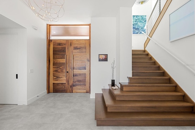 stairway featuring concrete floors and a chandelier