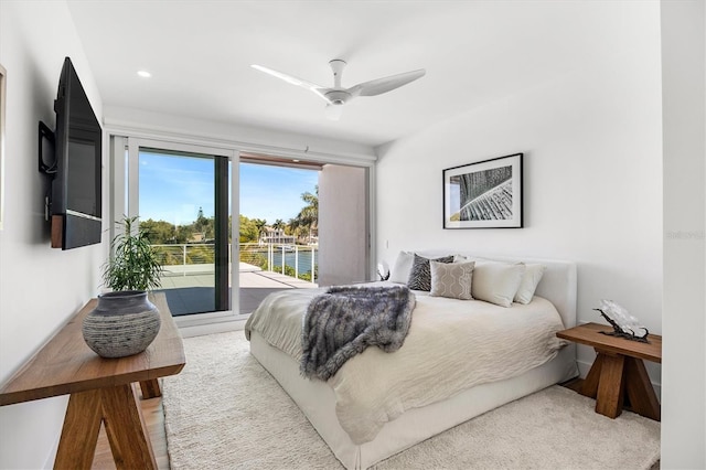 carpeted bedroom featuring ceiling fan and a water view