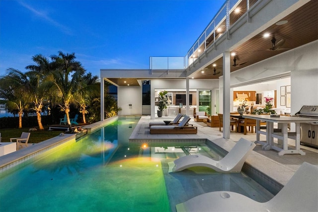 pool at dusk with a patio area, ceiling fan, a jacuzzi, and an outdoor living space