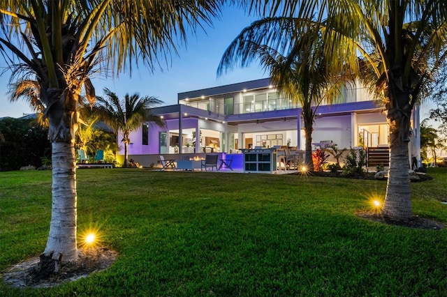 rear view of property featuring a lawn and a balcony