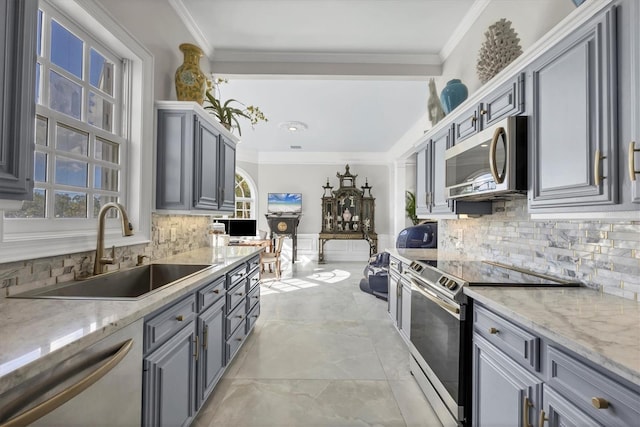 kitchen with appliances with stainless steel finishes, light stone countertops, gray cabinets, and sink