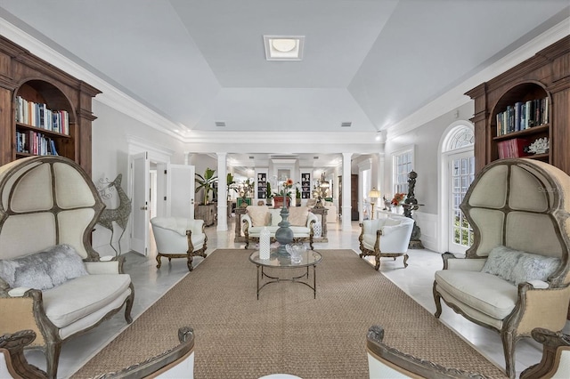 living area with crown molding, a raised ceiling, and ornate columns