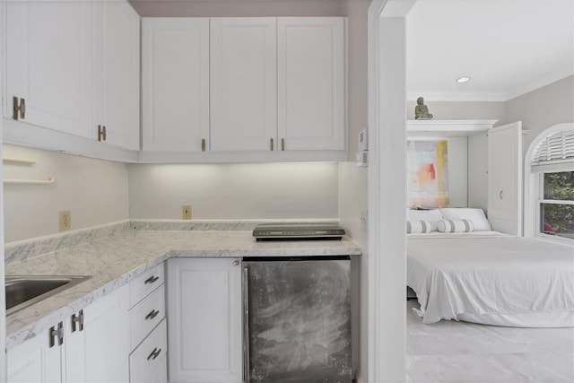 kitchen featuring light stone countertops, white cabinets, fridge, ornamental molding, and sink