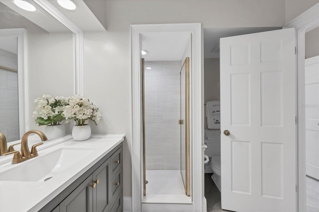 bathroom with vanity, a shower with shower door, and toilet