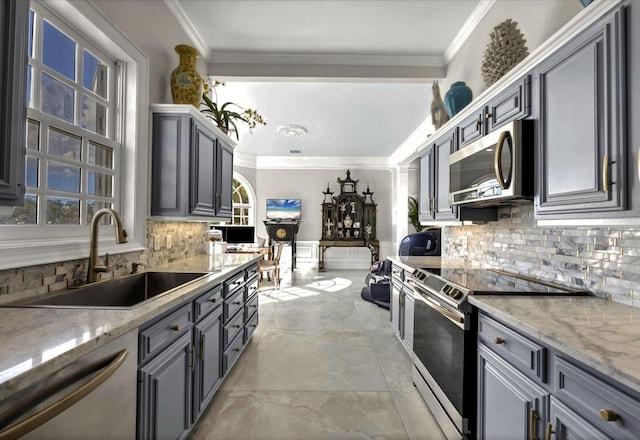 kitchen with gray cabinets, appliances with stainless steel finishes, sink, and light stone counters