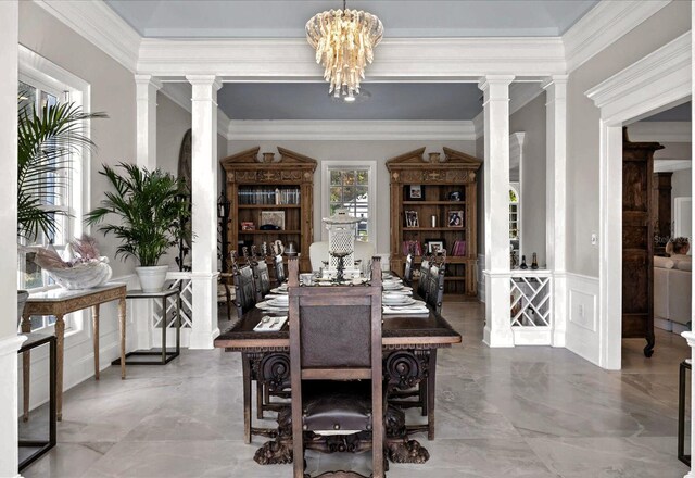 dining space featuring an inviting chandelier, crown molding, and decorative columns