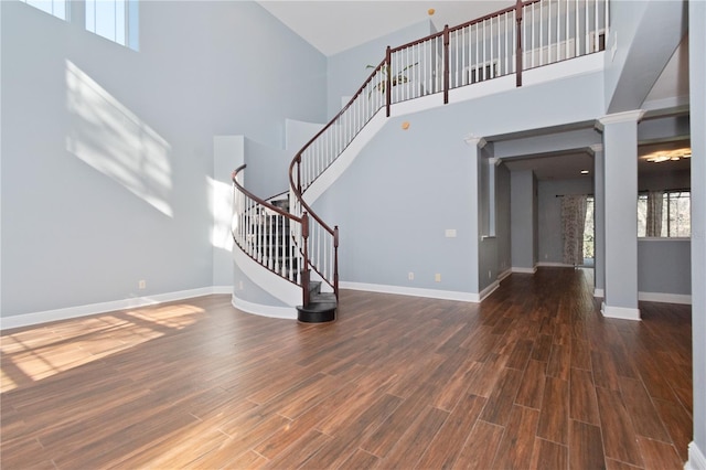 interior space with dark hardwood / wood-style flooring, ornate columns, and a towering ceiling