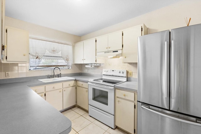 kitchen featuring white range with electric cooktop, sink, tasteful backsplash, light tile patterned floors, and stainless steel refrigerator