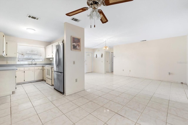 kitchen featuring white cabinets, white stove, light tile patterned floors, and stainless steel refrigerator