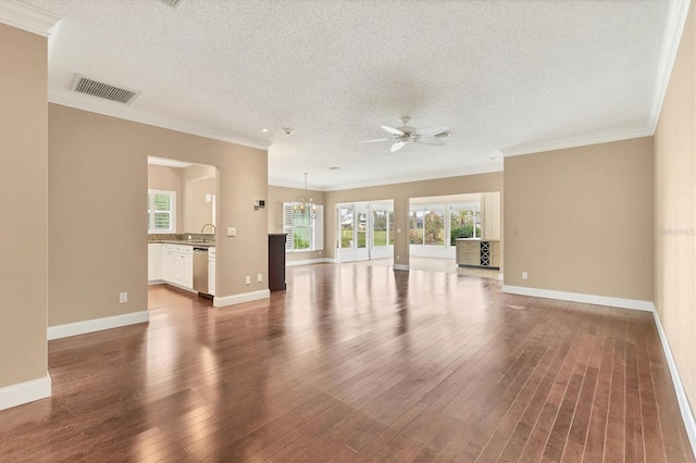 unfurnished living room featuring a textured ceiling, ceiling fan with notable chandelier, crown molding, and dark wood-type flooring