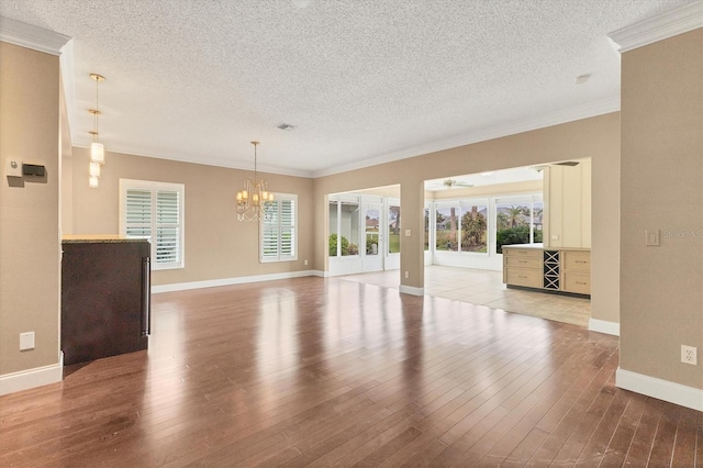 spare room featuring a textured ceiling, light wood-type flooring, and ornamental molding