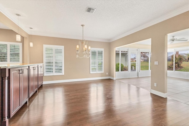 unfurnished dining area featuring ceiling fan with notable chandelier, a textured ceiling, dark hardwood / wood-style flooring, and ornamental molding