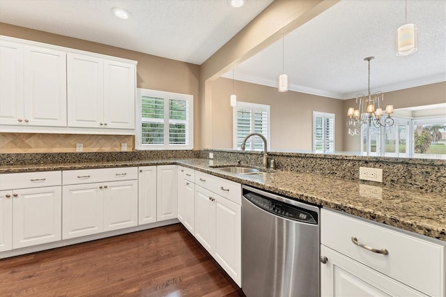 kitchen featuring white cabinetry, sink, stainless steel dishwasher, dark stone counters, and decorative light fixtures