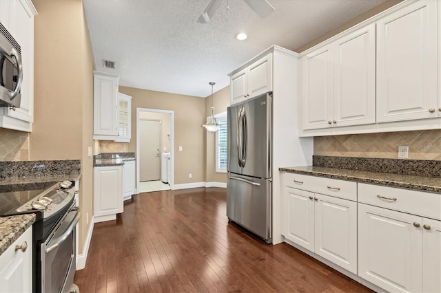 kitchen with appliances with stainless steel finishes, dark hardwood / wood-style floors, white cabinetry, and dark stone countertops