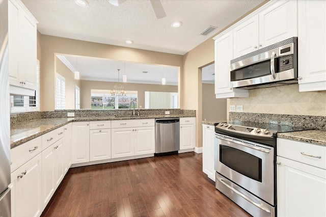 kitchen with appliances with stainless steel finishes, ornamental molding, dark wood-type flooring, sink, and white cabinetry