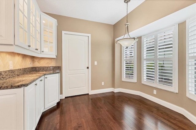 kitchen with white cabinets, hanging light fixtures, dark hardwood / wood-style floors, decorative backsplash, and dark stone countertops