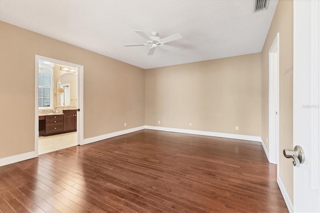 unfurnished bedroom with ensuite bath, ceiling fan, dark hardwood / wood-style flooring, and a textured ceiling