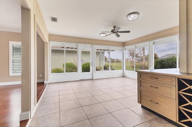 unfurnished sunroom featuring ceiling fan