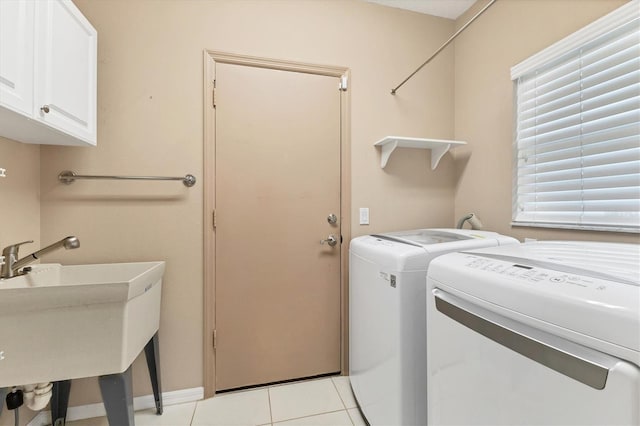 laundry area with cabinets, light tile patterned floors, washer and dryer, and a healthy amount of sunlight