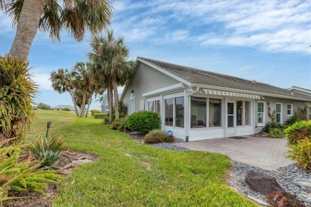 view of side of home featuring a sunroom and a lawn