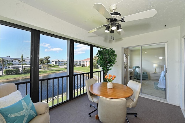 sunroom with a water view, ceiling fan, and a residential view