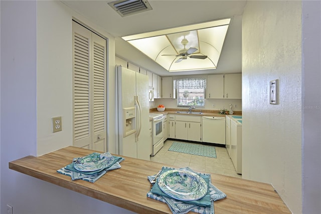 kitchen with a peninsula, white appliances, visible vents, and a sink