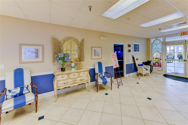 interior space featuring a paneled ceiling, tile patterned flooring, and baseboards