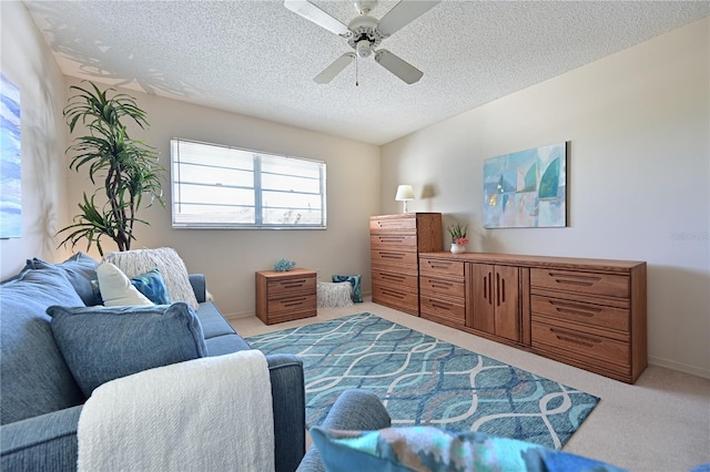 sitting room with a textured ceiling, ceiling fan, baseboards, and light colored carpet