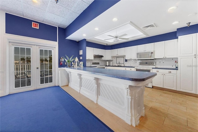 kitchen featuring white appliances, dark countertops, visible vents, and white cabinets