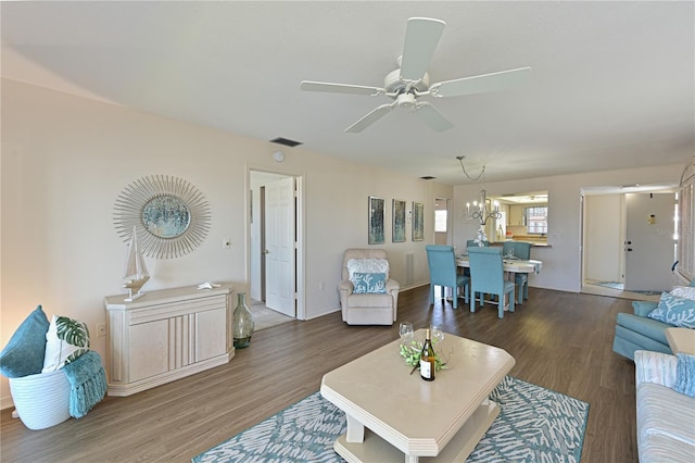 living area with ceiling fan with notable chandelier, dark wood-style flooring, and visible vents