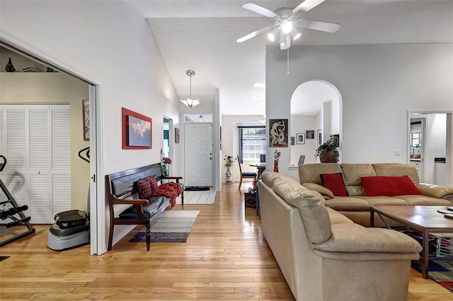 living room with high vaulted ceiling, a textured ceiling, ceiling fan, and light hardwood / wood-style flooring