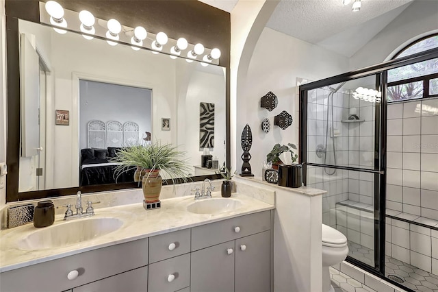 bathroom featuring toilet, vaulted ceiling, a textured ceiling, an enclosed shower, and vanity