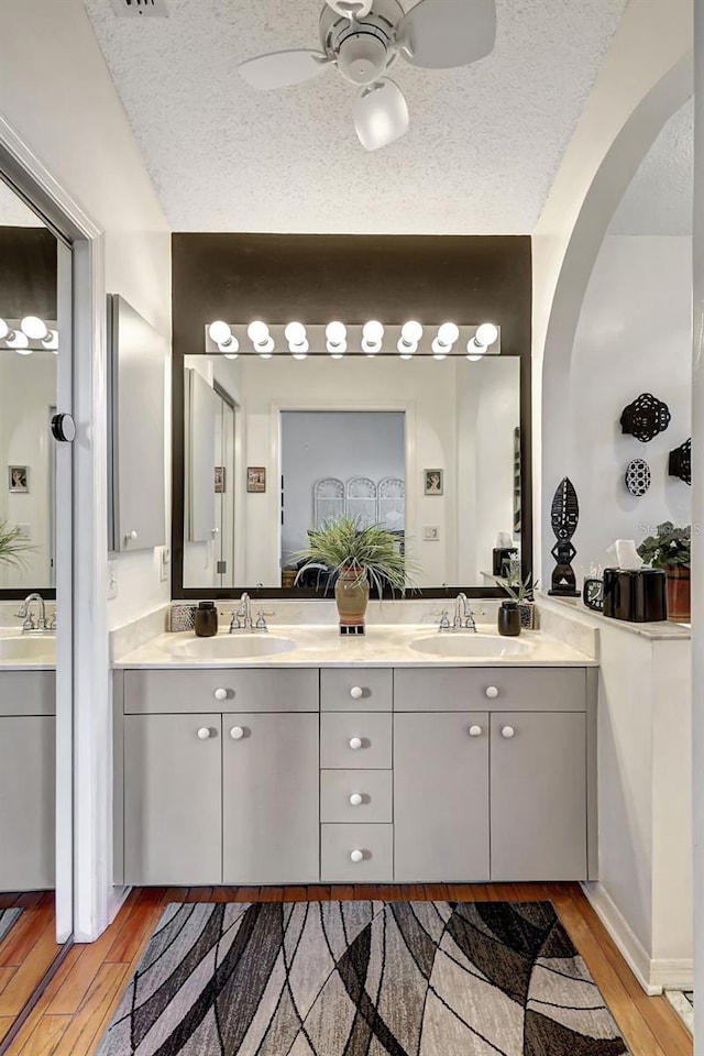 bathroom featuring hardwood / wood-style floors, ceiling fan, a textured ceiling, and vanity