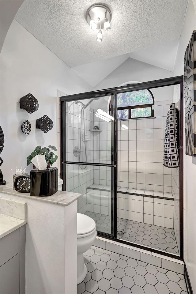 bathroom with walk in shower, a textured ceiling, tile patterned floors, and lofted ceiling