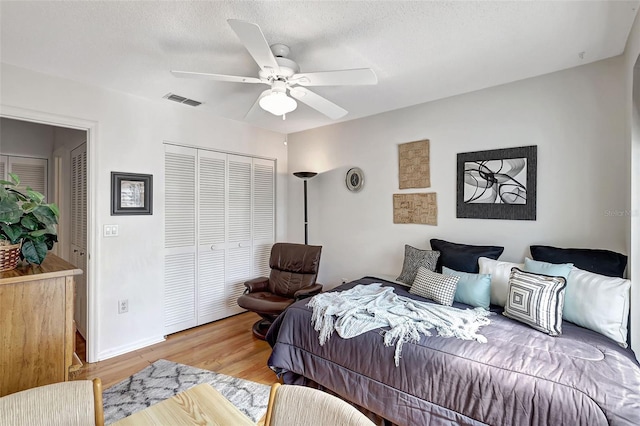 bedroom with hardwood / wood-style flooring, ceiling fan, a textured ceiling, and a closet