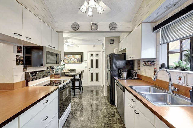 kitchen with stainless steel appliances, a textured ceiling, sink, and white cabinetry