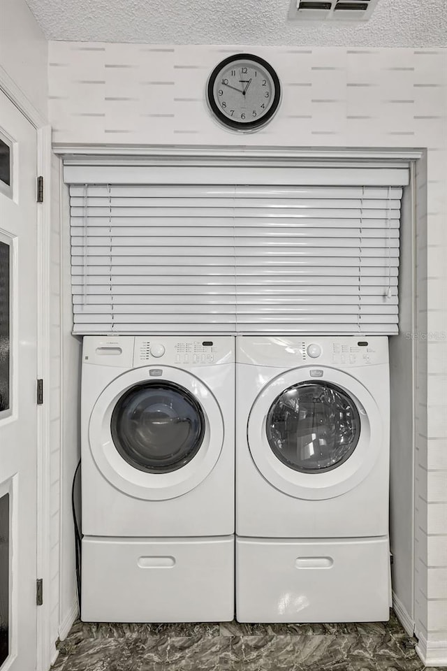 laundry room featuring washing machine and dryer and a textured ceiling