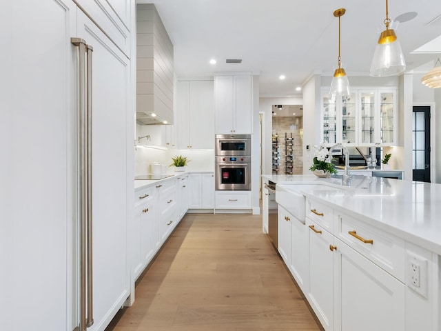 kitchen with white cabinets, decorative light fixtures, light hardwood / wood-style floors, and stainless steel appliances