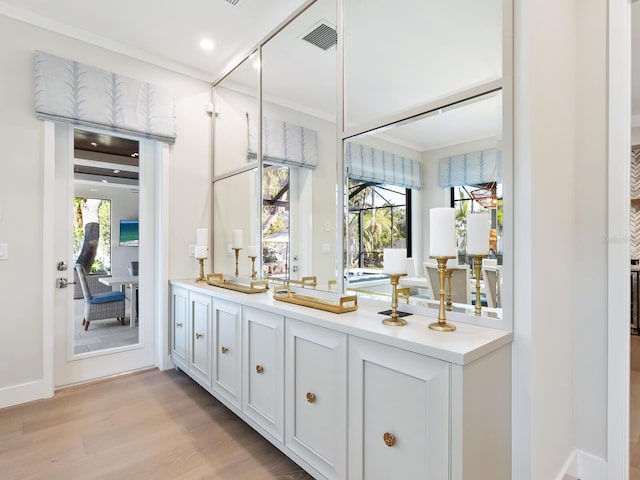 bar with white cabinets and light wood-type flooring