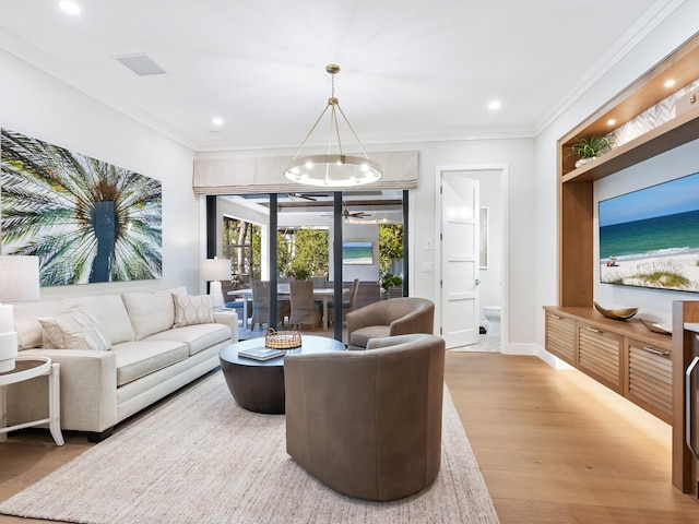 living room with ceiling fan with notable chandelier, light wood-type flooring, and ornamental molding