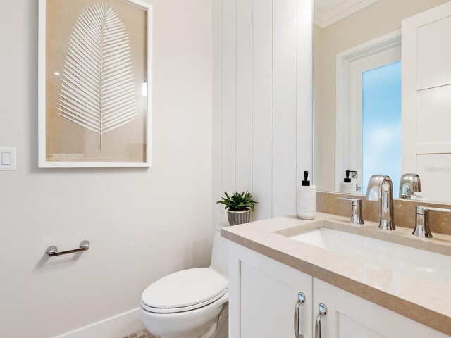 bathroom featuring vanity, ornamental molding, and toilet