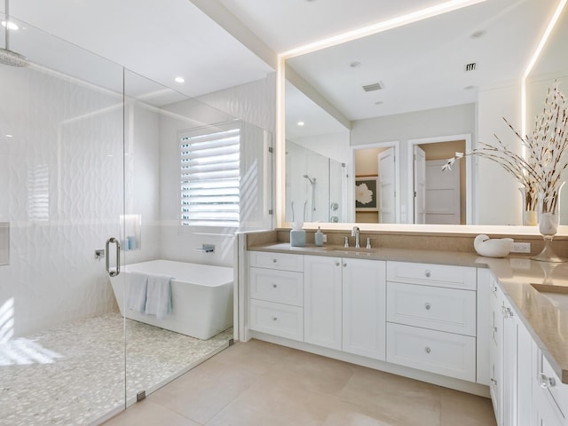 bathroom featuring plus walk in shower, vanity, and tile patterned flooring