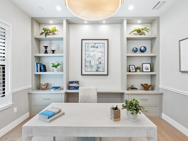 home office featuring built in shelves and light hardwood / wood-style floors