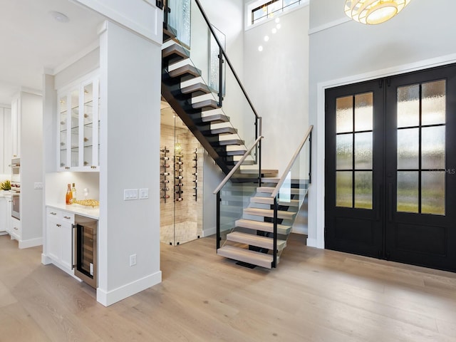 foyer featuring bar, wine cooler, french doors, and light hardwood / wood-style floors